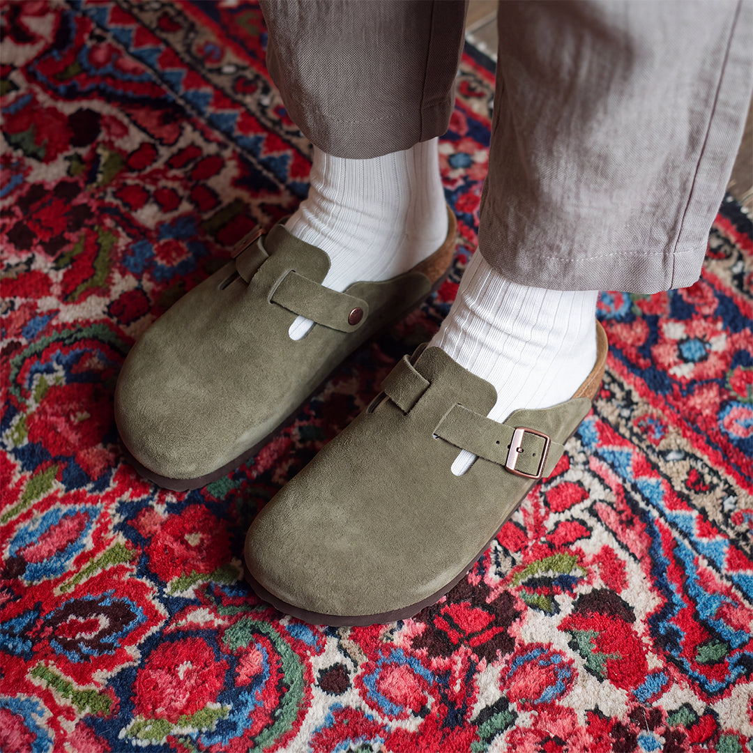 Black suede clogs worn with chunky knit socks on autumn steps